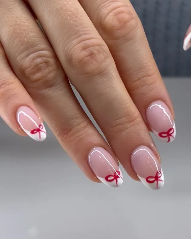 Sheer pink nails with white French tips and red bows